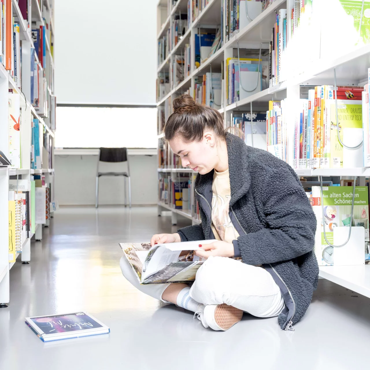 Eine Frau blättert in einem Buch in der Campus-Bibliothek.